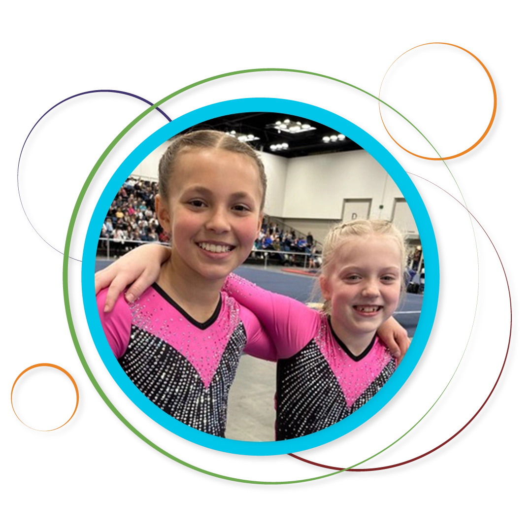 Two girls smiling at camera in gymnastics leotard