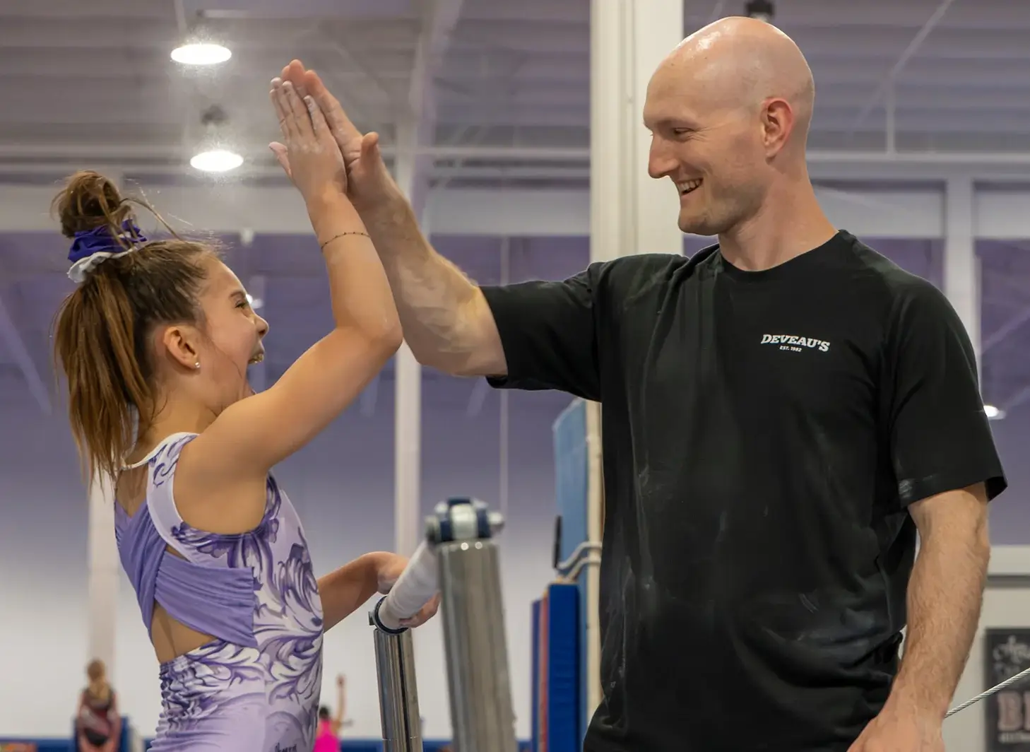DeVeau's coach giving a high five to a gymnast