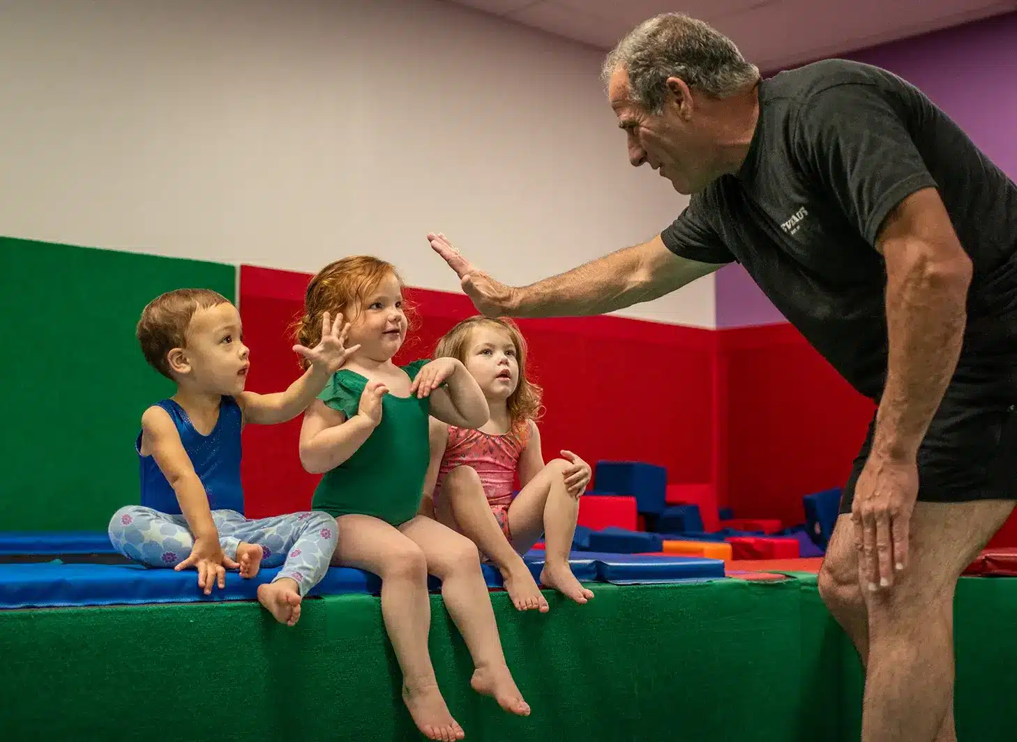 DeVeaus coach giving a high five to preschool gymnastics students