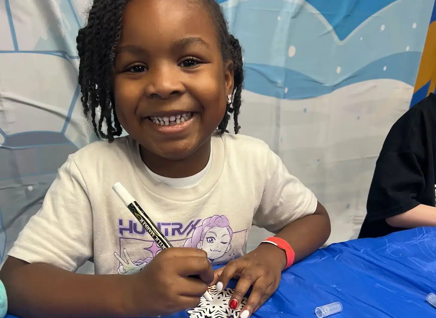Girl smiling at camera coloring on a snowflake paper